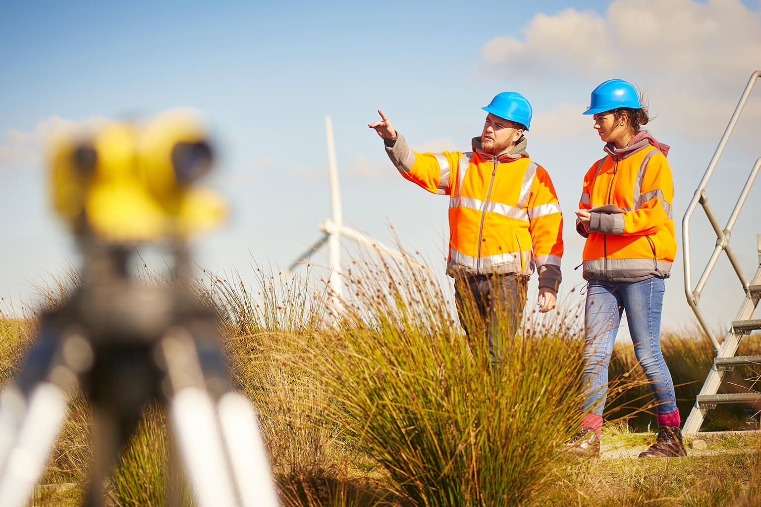 People in safety gear walking by wind turbines