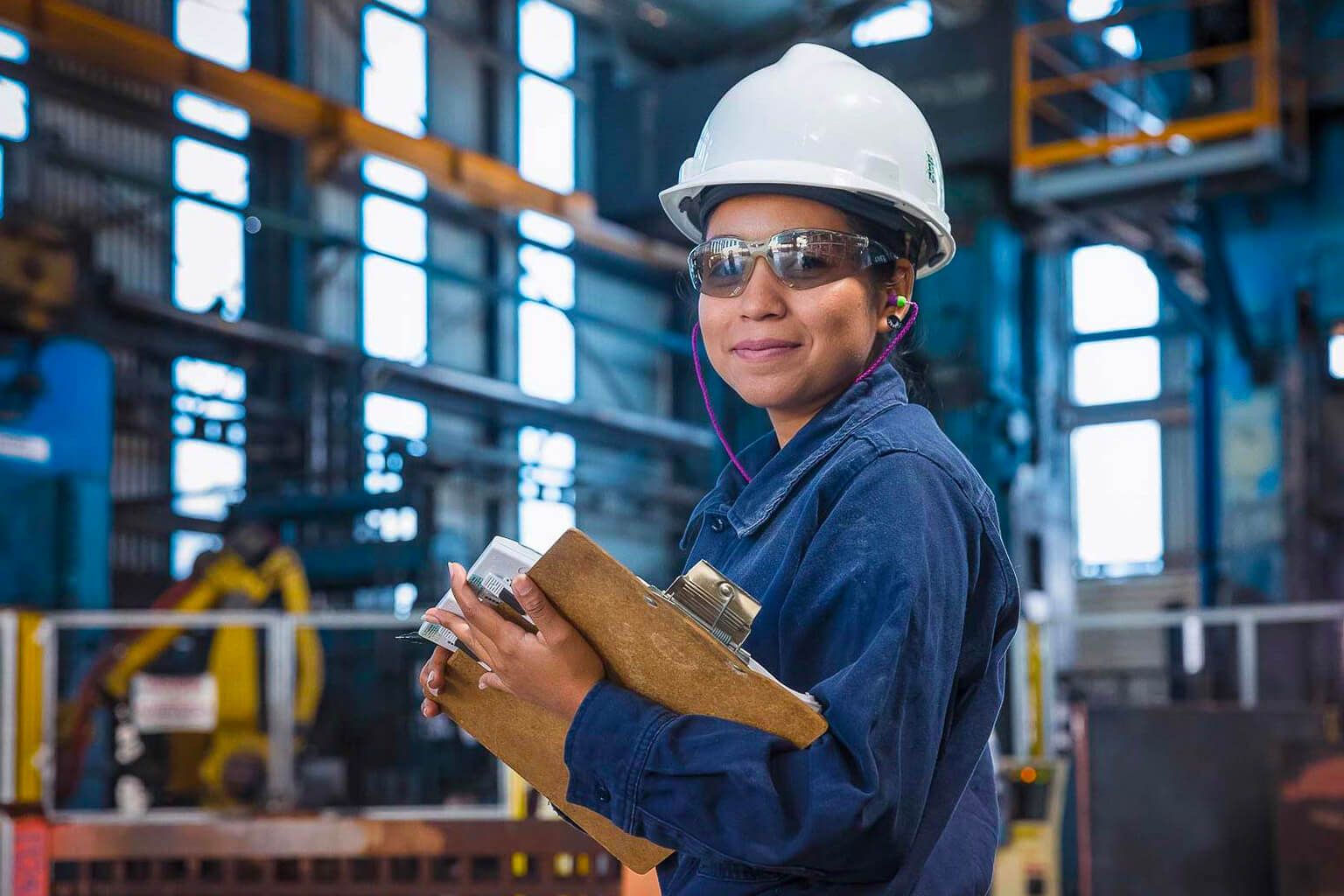 Person wearing safety gear holding a clipboard