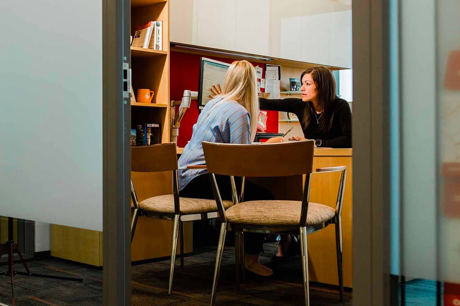 People on either side of a desk in a cubicle