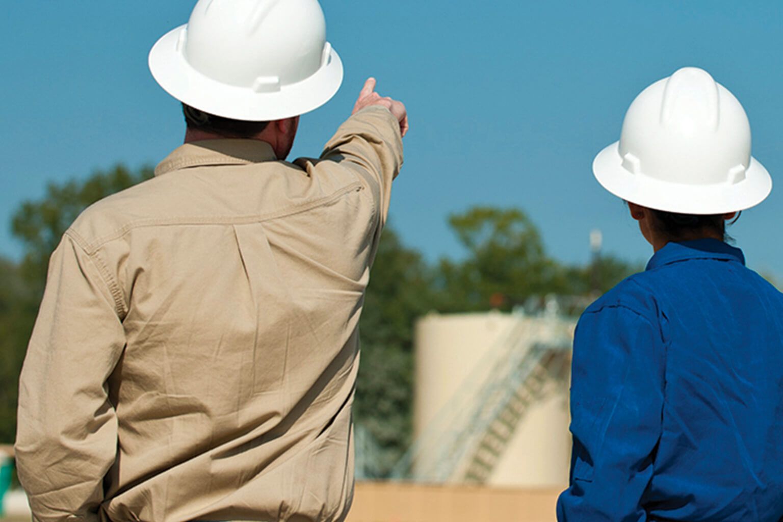 Two people wearing hard hats looking at the sky