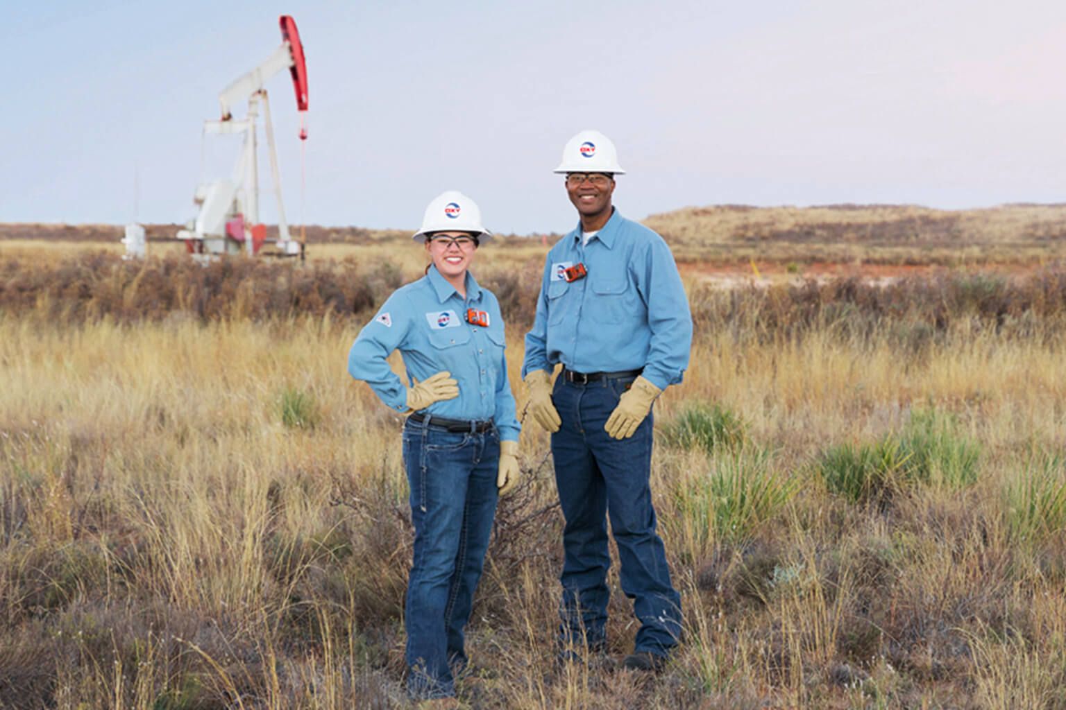Two people wearing work uniform standing in field