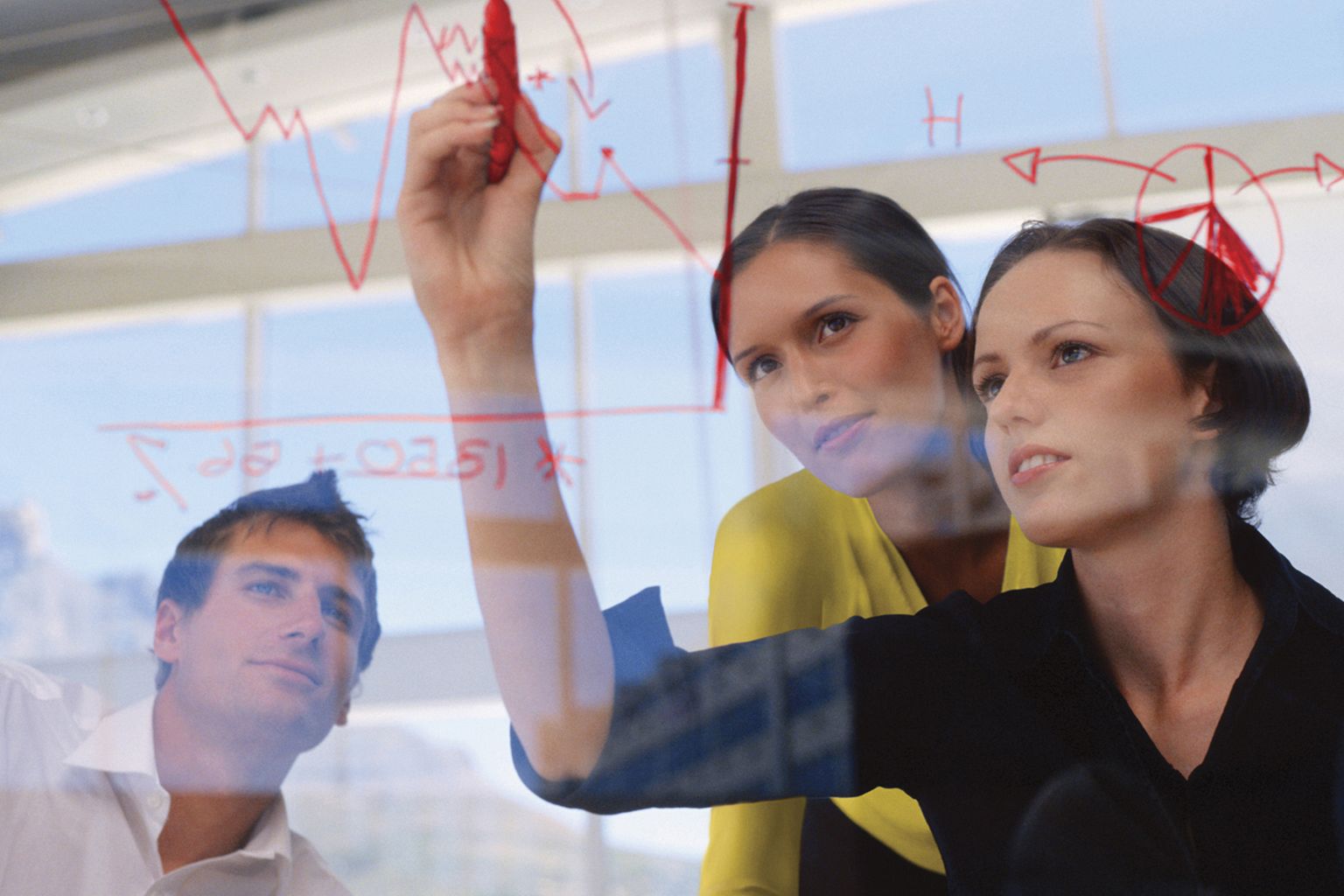 People writing on a glass whiteboard