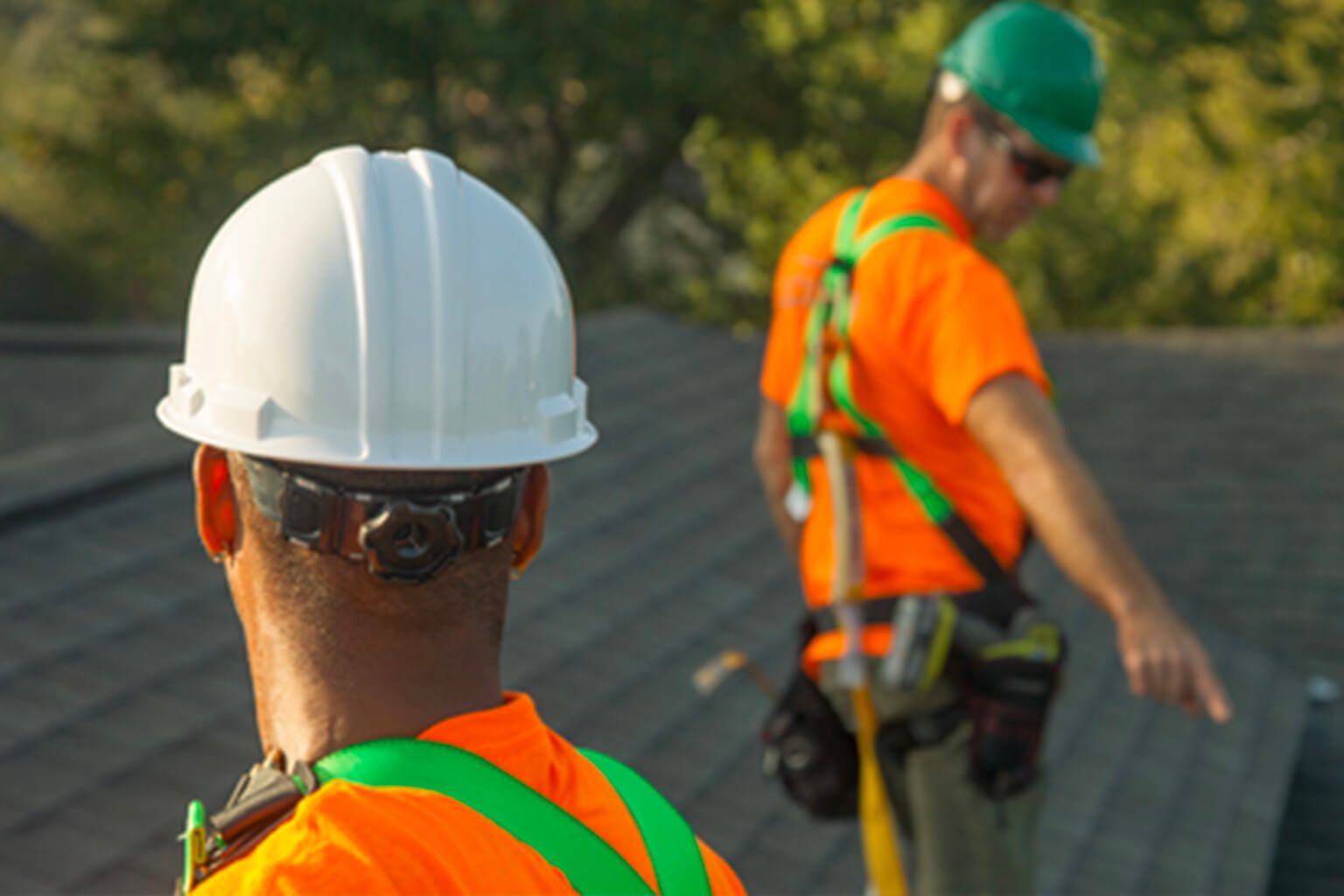 Two people wearing hardhats and reflective gear