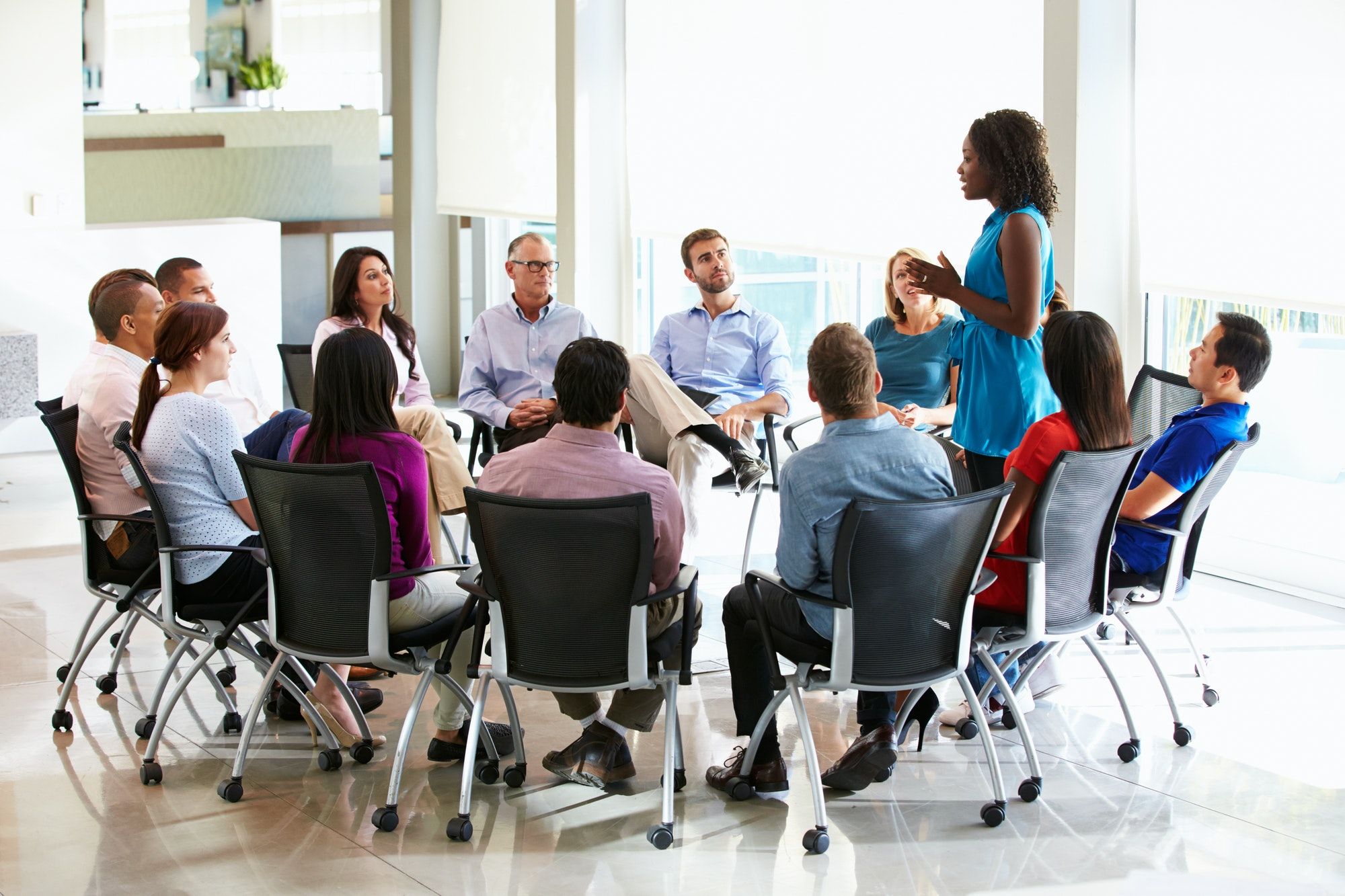 businesswoman-addressing-multi-cultural-office-staff-meeting